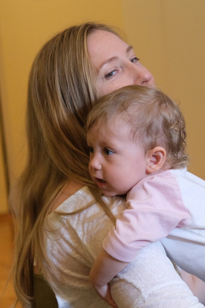 A lovely mother looks lovingly as she holds her young daughter close to her shoulder, while the child holds the mother's arm gently.